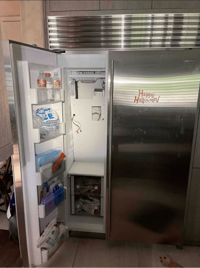 Sub-Zero repair near me in Miami — Sub-Zero side-by-side built-in refrigerator mid-service by a local Miami technician in a real Miami family home — child&rsquo;s Halloween sticker still on the door