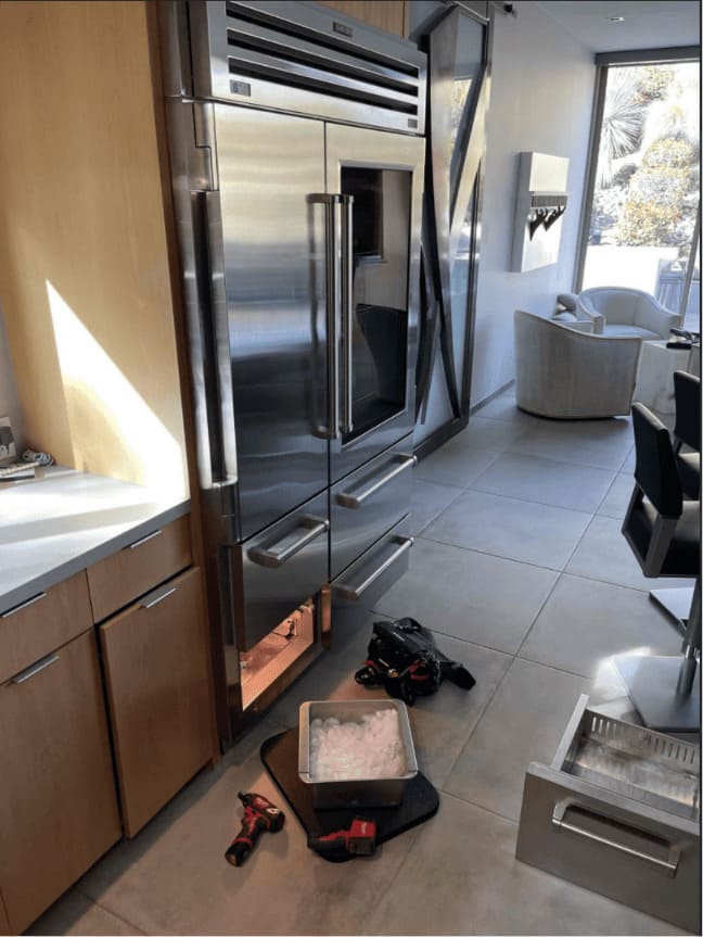 French-door Sub-Zero refrigerator with ice maker mid-repair by a local technician in a modern Miami luxury home