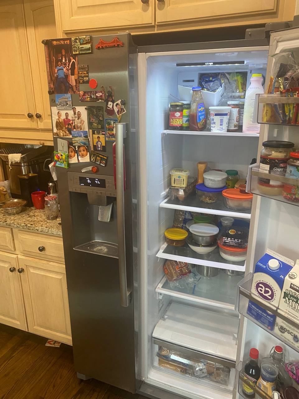 Sub-Zero repair near me in Miami — Real Miami family side-by-side fridge mid-service &mdash; kids&rsquo; magnets and family photos on the door, food kept in place during the visit