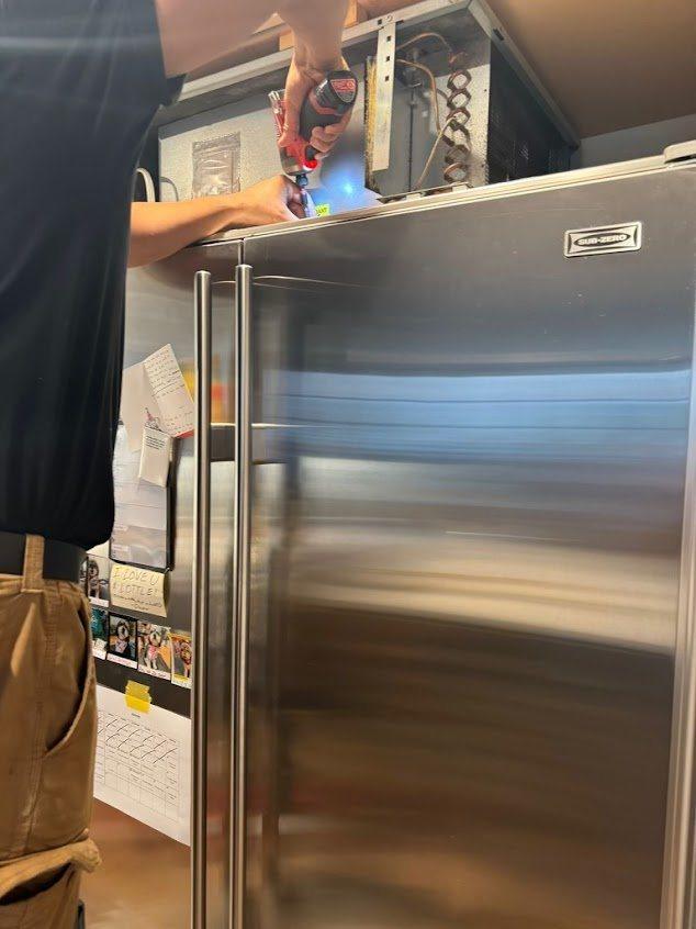 Technician servicing the condenser of a Sub-Zero built-in