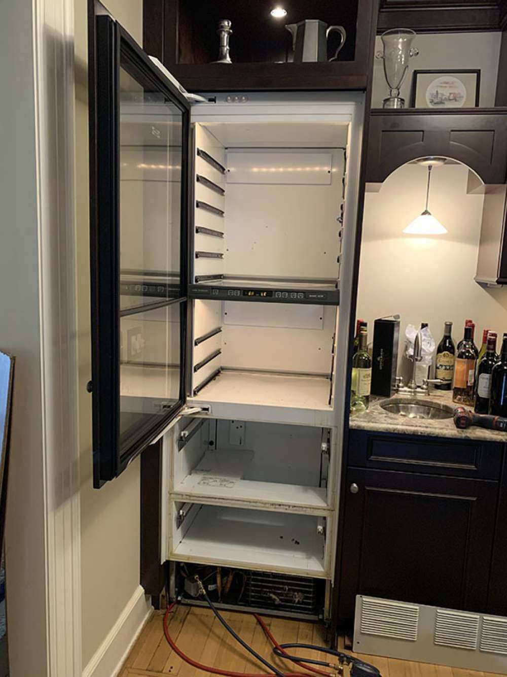 Tall built-in Sub-Zero wine column opened for repair in a Miami home